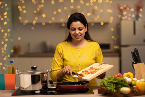Portrait of Indian woman enjoying while cooking meal in the kitchen